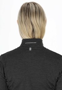 Giacca nera texture con colletto alto, dotata di un piccolo anello per appendere e il logo "SWEDEMOUNT" sul retro. Finitura in tessuto liscia.