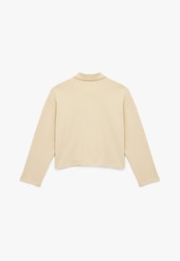 Beige cropped sweatshirt med lange ærmer og krave, der kan foldes ned. Glat tekstur og minimalistisk design, vist fra bagsiden.