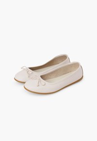 Paire de ballerines couleur crème avec petits nœuds décoratifs et semelles couleur cuir sur fond blanc.