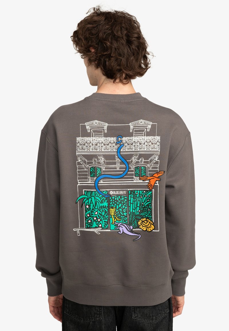 Sudadera gris con un gráfico colorido en la parte posterior que muestra un edificio con plantas y animales, contorneado en blanco y acentuado con azul, naranja y púrpura.