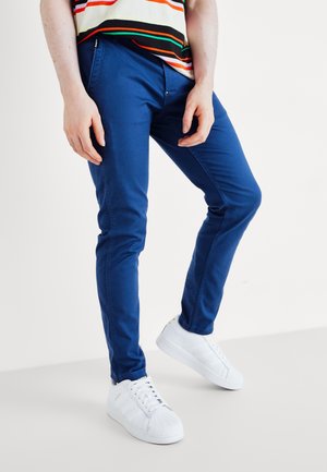 Blue slim-fit chinos made of cotton blend, featuring a smooth texture. Paired with white sneakers, showcasing a minimalist design.