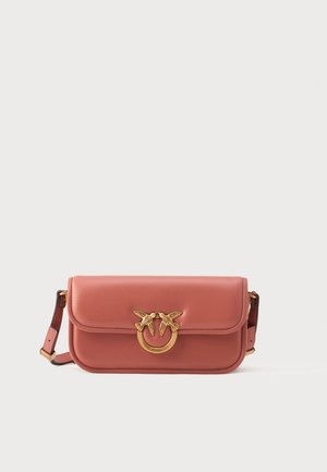 Sac à main en cuir rose avec une fermeture à double oiseau et un anneau doré. Il dispose d'un rabat supérieur et d'une bandoulière réglable, avec une texture lisse.