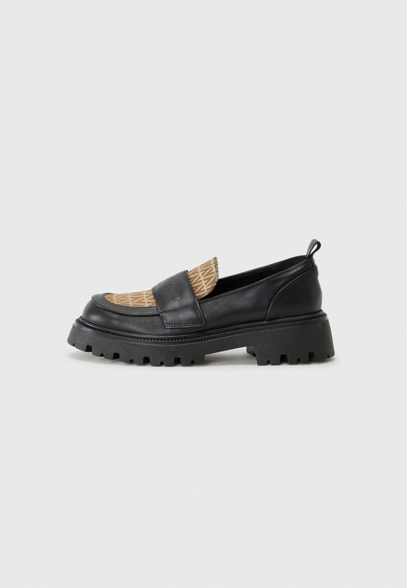 Black loafers with a textured tan pattern across the vamp. Chunky rubber sole and a slight heel, featuring a back pull tab for easy wear.