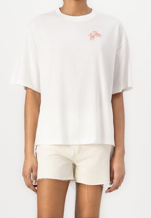 Biała bawełniana koszulka z krótkim rękawem i luźnym krojem, z małym graficznym motywem pomarańczowego kraba na lewej stronie klatki piersiowej.