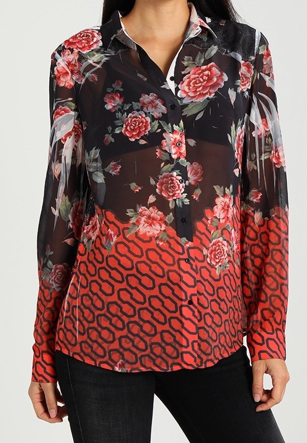 Blouse noire transparente à manches longues avec motif floral rouge et rose en haut et imprimé géométrique rouge en bas, portée avec un pantalon noir.