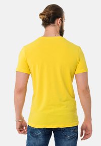 Yellow short-sleeve t-shirt made of cotton, featuring a crew neck and a relaxed fit. Smooth texture, no visible patterns or hardware.