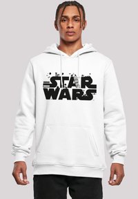 Hvit hettegenser i bomullsblanding med frontlomme. Svart "STAR WARS"-logo med intrikate grafiske elementer og illustrasjoner i bokstavene.