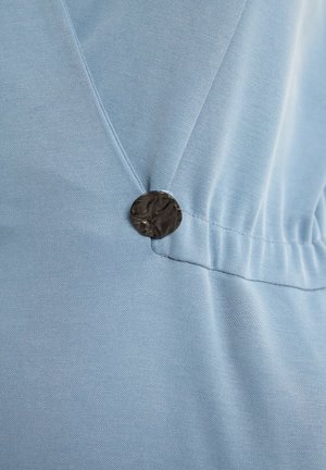Jasnoniebieska tkanina o gładkiej fakturze, z ciemnym, teksturowanym guzikiem akcentującym marszczenie.