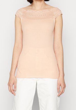 Perzikkleurige ribgebreide tanktop met doorschijnende kanten rand op de schouders, met een aangesloten pasvorm en zachte textuur, gecombineerd met witte, wijd uitlopende broek.