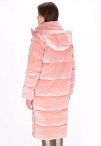 Długi pikowany płaszcz z miękkiego, różowego sztruksu z kapturem, z poziomym pikowaniem, bocznymi rozcięciami i ściągaczami przy mankietach.