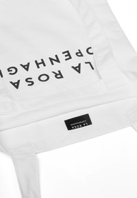 Bolso tote blanco con el texto negro "LA ROSA COPENHAGEN" impreso verticalmente. El material parece ser algodón y cuenta con dos asas resistentes, con una etiqueta textil visible.