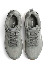 Grå idrottsskor med ett texturerat mesh-överdrag, vadderad tunga och snören. Har en lätt sula med en brun gummibeläggning på botten.