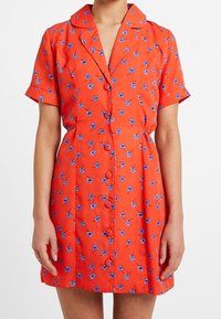 Kortärmad orange klänning med blå blommönster, krage och knappstängning. Lättviktigt tyg med figurnära midja och längd ovanför knäet.