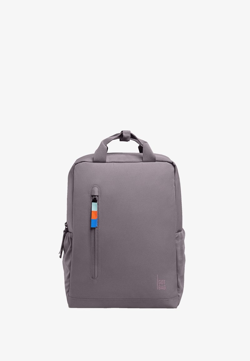 Sac à dos rectangulaire violet clair avec poignées supérieures, poche zippée verticale à l'avant avec languette colorée, et poches latérales élastiques.