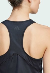 Black athletic tank top with a racerback design, featuring a textured logo and stitching details along the seams and back panel.