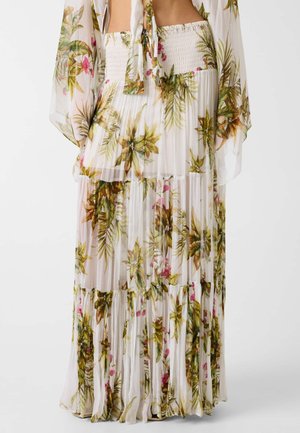 Longue jupe maxi blanche transparente avec imprimé tropical de feuilles vertes et roses et fleurs, design à étages et taille smockée.