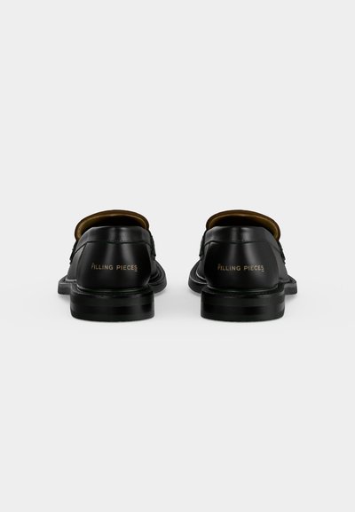 Ζευγάρι μαύρα δερμάτινα loafers με επίπεδα τακούνια εμφανιζόμενα από πίσω, με το λογότυπο "FILLING PIECES" σε χρυσά γράμματα.