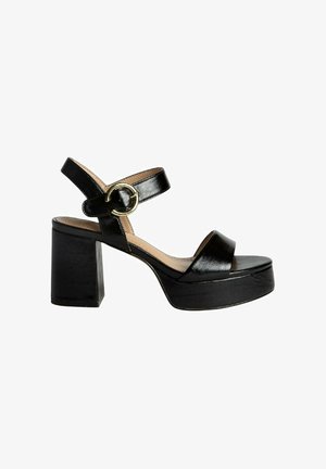 Sandalias de tacón alto negras con un grueso tacón cuadrado. Presenta una correa para el tobillo con una hebilla circular dorada y una amplia correa frontal. Acabado en piel lisa.