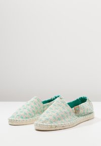 Espadrillas con motivo realizzate in tessuto leggero nei colori verde menta e crema. Presentano una suola in juta intrecciata e un accento logo laterale.