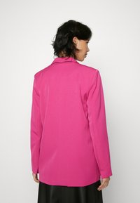 Fuchsia blazer with a notch lapel, long sleeves, and tailored fit. Smooth texture, single back vent, and clean stitching details.