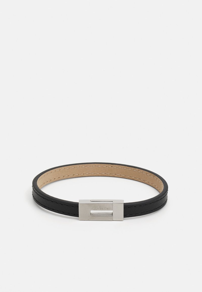 Black leather bracelet with a smooth texture, featuring a silver metal clasp. The interior is tan, highlighted by stitched detailing.
