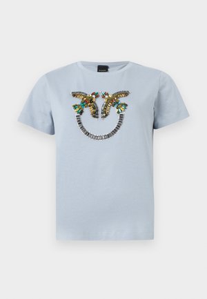 Γαλάζιο κοντομάνικο πουκάμισο με πολύχρωμο σχέδιο από χάντρες που απεικονίζει δύο πουλιά που κοιτάζονται μεταξύ τους πάνω από μια καμπυλωτή σειρά ασημένιων χαντρών.