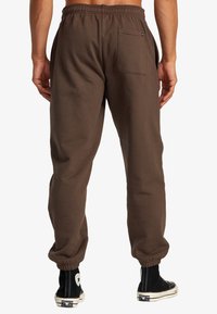 Braune Jogginghose mit elastischem Bund, schmal zulaufenden Bündchen und einer Gesäßtasche. Der Stoff hat eine glatte Textur und bietet eine lockere Passform.