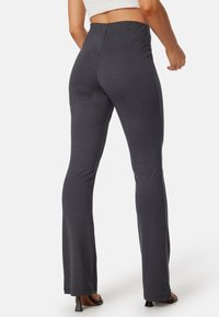 Leggings svasati di un grigio scuro con una texture liscia e una vita alta, caratterizzati da un design aderente che si estende dai fianchi fino alla caviglia.