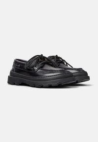 Black leather boat shoes with round laces, moccasin-style stitching, and rugged rubber outsoles for traction. Features a low-cut design.