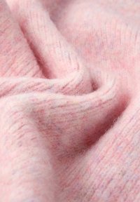Tessuto di lana rosa con una texture morbida e lanosa, caratterizzato da una leggera fusione di colori pastello e da un motivo a coste, che mette in risalto pieghe ondulate.