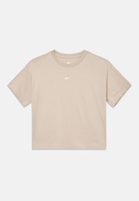 Beżowy krótki T-shirt Nike z krótkimi rękawami i małym białym logo swoosh Nike umieszczonym na środku klatki piersiowej, na białym tle.