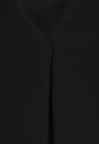 Close-up of black fabric with overlapping V-neck design and smooth texture.