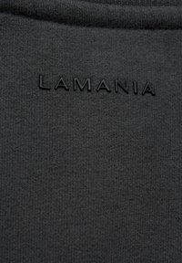 Čierna tkanina s textúrovaným pleteným vzorom; obsahuje debossované logo "LAMANIA" v zodpovedajúcom čiernom odtieni.