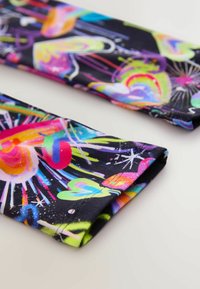 Farebná látka s živými abstraktnými vzormi v ružovej, zelenej a modrej farbe na čiernom pozadí; flexibilná a hladká textúra.