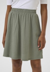 Gonna verde a lunghezza ginocchio realizzata in tessuto strutturato con cintura elastica, caratterizzata da morbide pieghe per una vestibilità comoda.