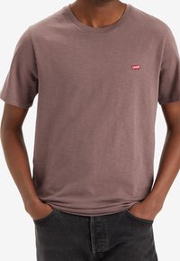 Kortärmad T-shirt med rund halsringning i dämpad brun färg. Tillverkad av mjukt material med en liten röd Levi's-logga på bröstet. Avslappnad passform, slät textur.