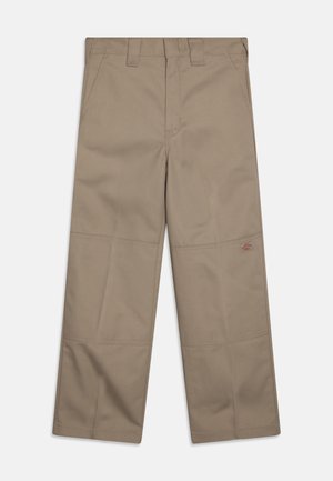 Beige weite Hosen aus robustem Stoff, mit zwei Fronttaschen und einem kleinen Logo an der Seite. Genähte Details entlang der Beine.