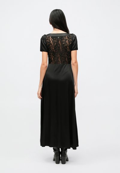 Lange zwarte jurk met een satijnen voorkant en een kanten paneel aan de achterkant, korte mouwen en een vloeiende silhouet. Getextureerde stof voegt detail toe.