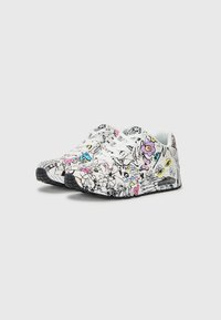 Witte sneakers met een zwart lijntekeningpatroon en kleurrijke accenten in roze, blauw en geel. Zwarte rubberen zool en witte veters.