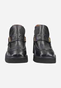 Schwarze Leder-Stiefeletten mit runder Spitze, ausgestattet mit einer stabilen Sohle, dekorativem goldenen Schmuck und einem Riemen mit eingeprägtem "DC".