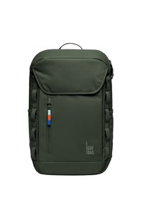 Sac à dos vert foncé avec une poche avant, des accents zippés, des sangles latérales et une étiquette bleu-rouge-blanc. Présente un design minimaliste et un logo.