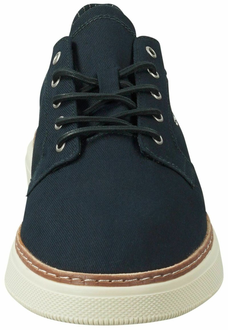 Marineblaue Segeltuch-Schnürschuhe mit einer hellbraunen Gummisohle, weißen Nähten und Metallösen. Flaches, rundes Zehen-Design mit strukturierter Oberfläche.