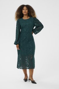 Teal lace dress with long balloon sleeves, knee-length, floral pattern, and a slightly transparent hem. Worn with black heeled shoes.