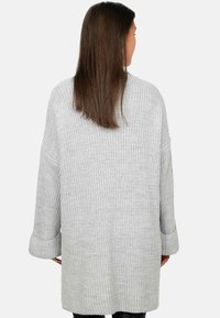 Maglione grigio chiaro oversize con maniche larghe, lavorazione a coste testurizzata e un fit rilassato, caratterizzato da un retro di lunghezza media e tessuto morbido.