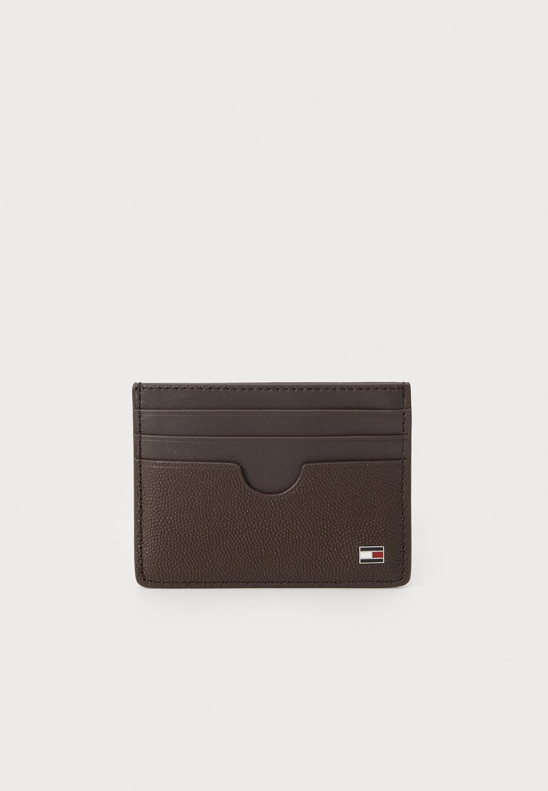 Porte-cartes din piele maro cu finisaj texturat, 4 sloturi pentru carduri și un accent cu logo în colțul din dreapta jos. Design minimalist.