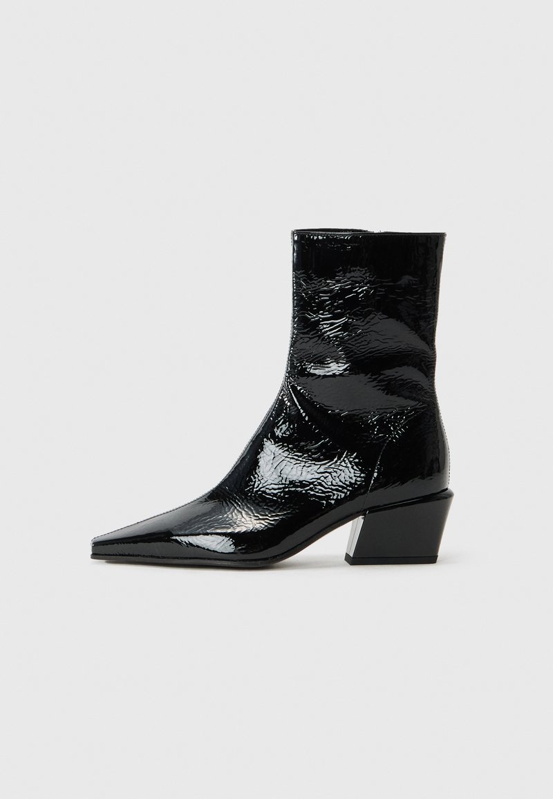 Bottines noires en cuir verni avec un bout pointu, une finition texturée et un talon bloc épais. Design épuré avec une surface lisse et brillante.