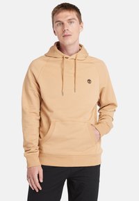 Beige hoodie med en kængurulomme, justerbar snøre-hætte og ribbede manchetter. Har et lille logo på brystet.