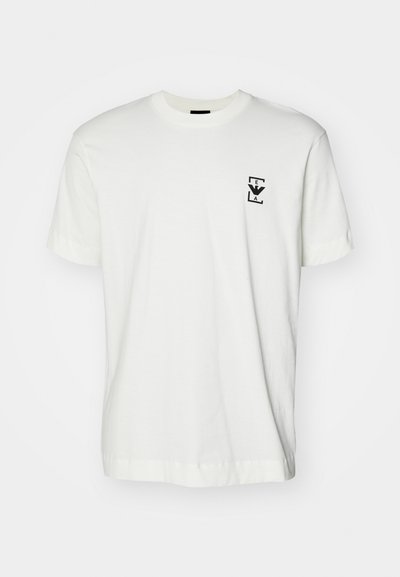 White cotton t-shirt with short sleeves and a round neck. Features a small black logo on the left chest. Smooth texture, casual fit.