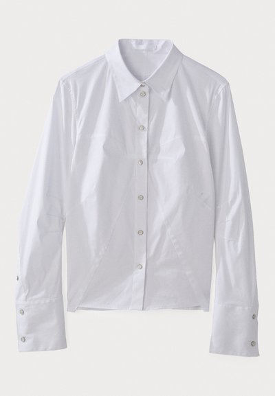 White long-sleeve shirt made of smooth fabric, featuring a pointed collar, front buttons, and structured seams for a tailored fit. Silver button accents.