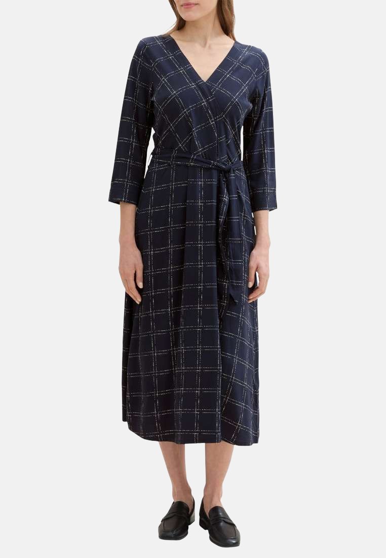Robe portefeuille bleu marine avec des manches trois-quarts, présentant un motif à carreaux blancs, une taille nouée et une longueur midi. Tissu lisse et léger.